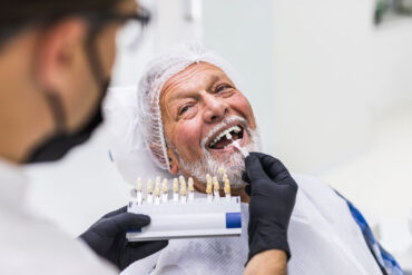 Senior man having dental implants fitted at dentist's office.